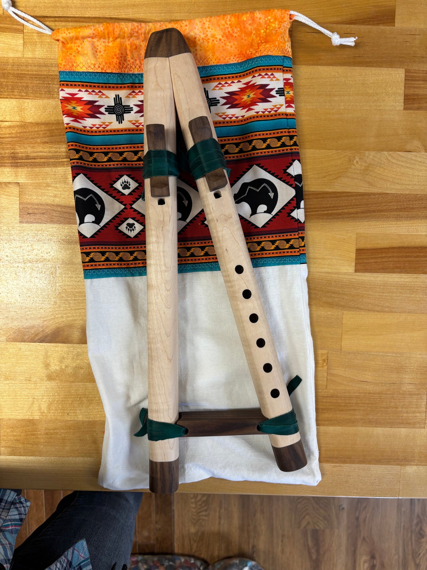 Two wooden flutes on a patterned fabric with a wooden floor background