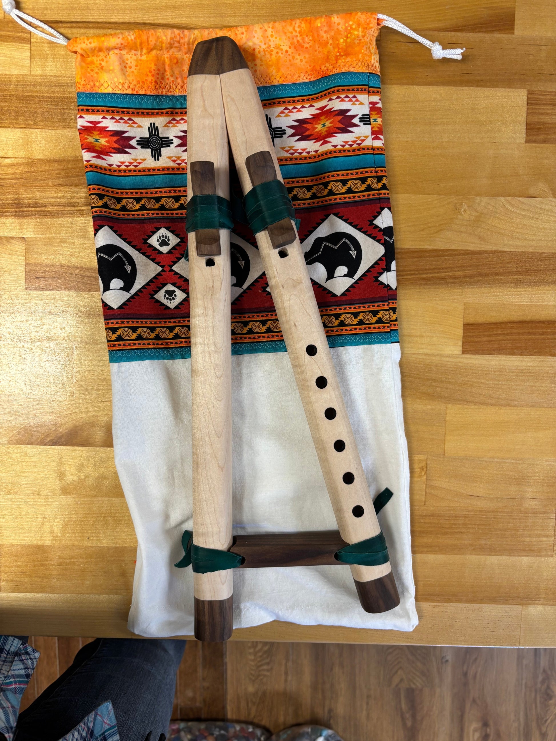 Two wooden flutes on a patterned fabric with a wooden floor background